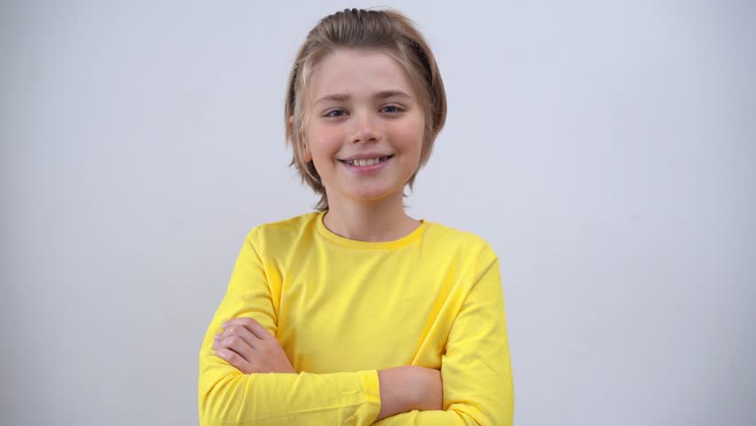 Portrait Of Smiling Handsome Teenager Boy Long Hair in Yellow T-Shirt Looking At Camera Over white Background. Positive Teen Mood. Advertising Copy Space