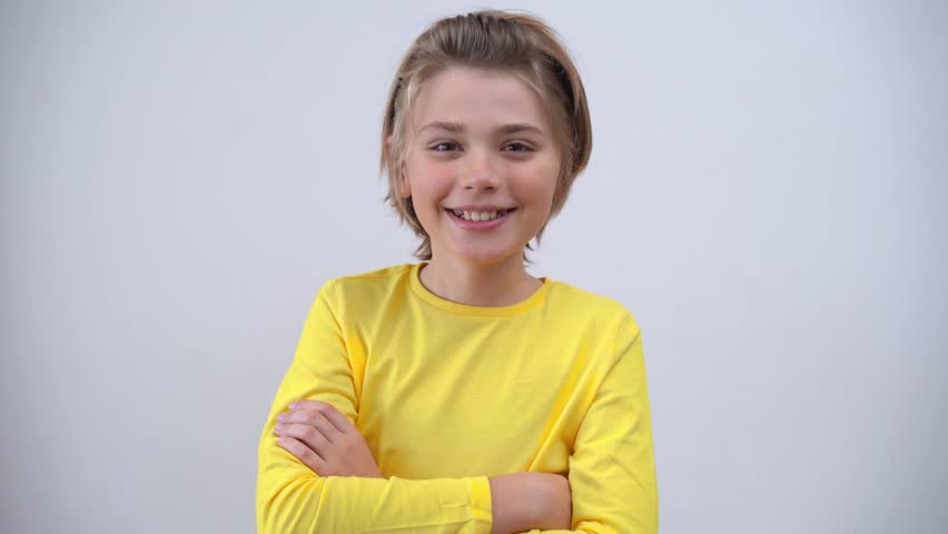 Portrait Of Smiling Handsome Teenager Boy Long Hair in Yellow T-Shirt Looking At Camera Over white Background. Positive Teen Mood. Advertising Copy Space