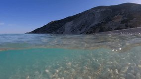 Underwater split video of famous paradise pebble beach of Myrtos one of the best in island of Kefalonia, Ionian, Greece