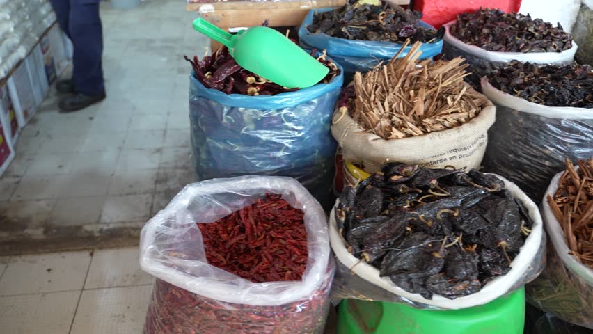 Large bags stuffed with spices and dried peppers at a local indoor farmers market in Mexico