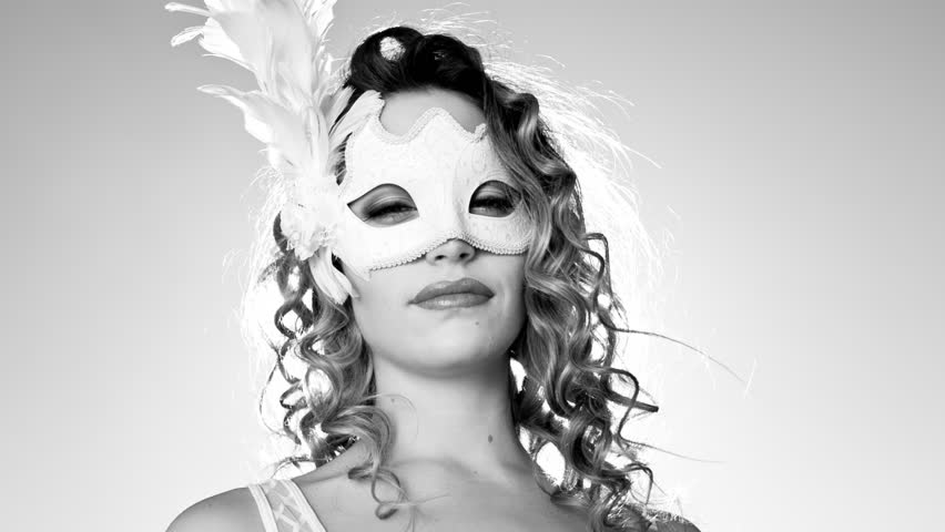 A beautiful woman wearing a masquerade mask and dancing outside