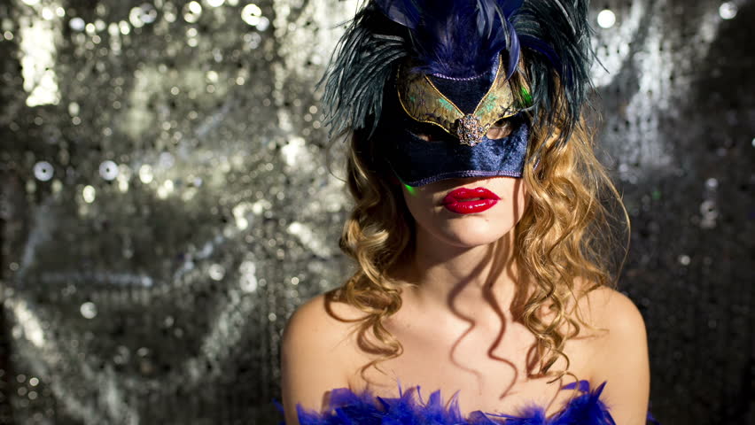 A beautiful woman wearing a gold masquerade mask and dancing