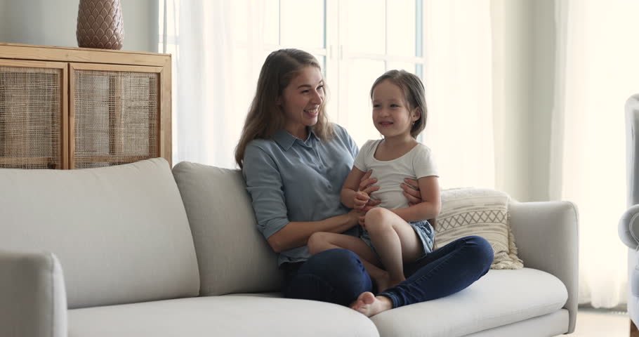 Cute little girl laughing seated on mums laps, enjoy funny playtime and communication with loving mother, relish pastime together on carefree weekend at cozy home. Happy motherhood, custody and love Royalty-Free Stock Footage #1099835259