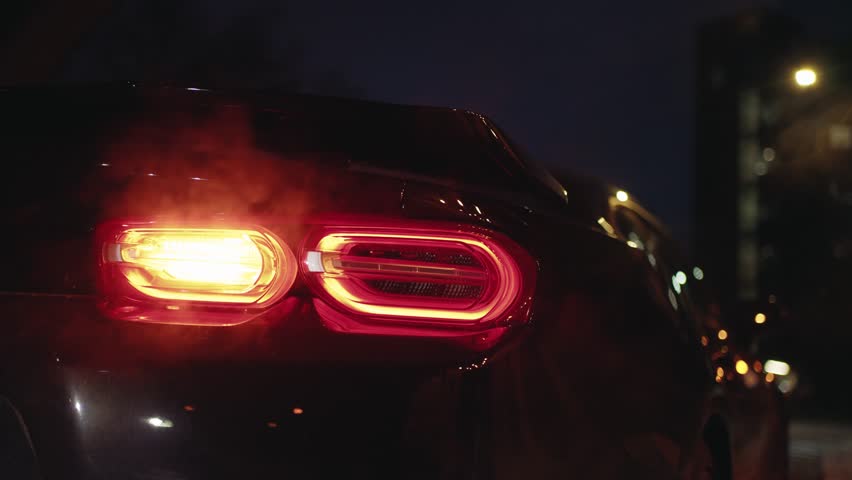 Black sports car tail light glowing in the dark of a night city