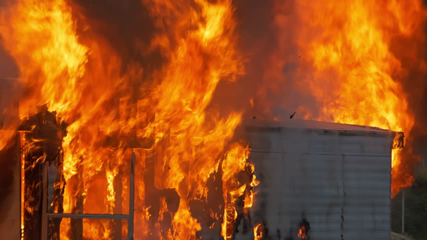 Close up detailed shot of flames engulfing a building. 4K footage of fire, embers, and ash debris.