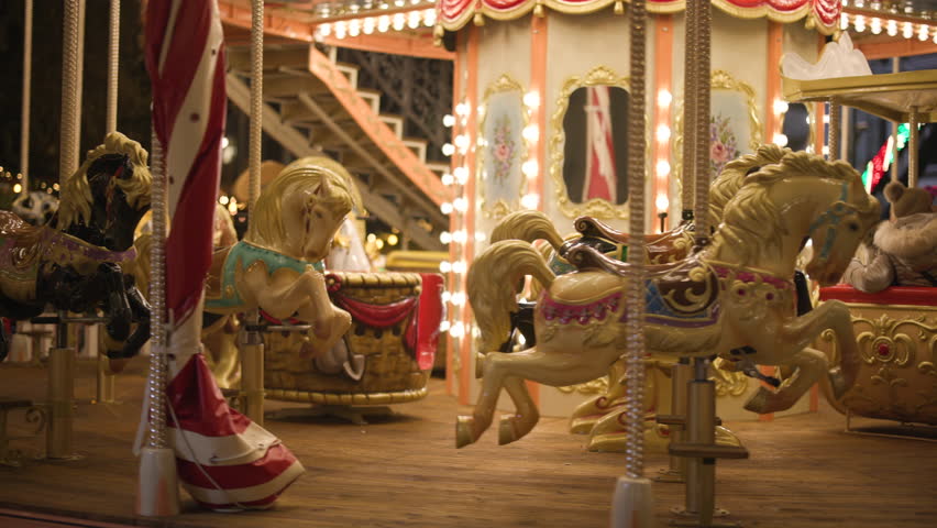 Traditional carousel running in the amusement park on the main square of a city. Close-up of beautifully decorated, running empty seats with vivid lights. High quality 4k footage