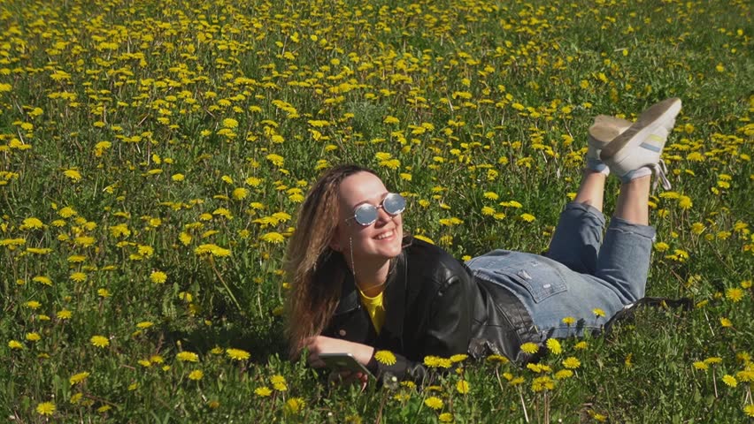 the girl lies in the park on the grass and enjoys the sun. High quality Full HD video recording