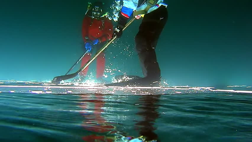 Hockey players in sports uniform with puck and stick outdoors underwater shooting under ice outdoors, active rest and sport as lifestyle on Lake Baikal. | Shutterstock HD Video #1099847217