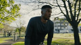Young black man in sports clothing exhaling during break between exercises in park