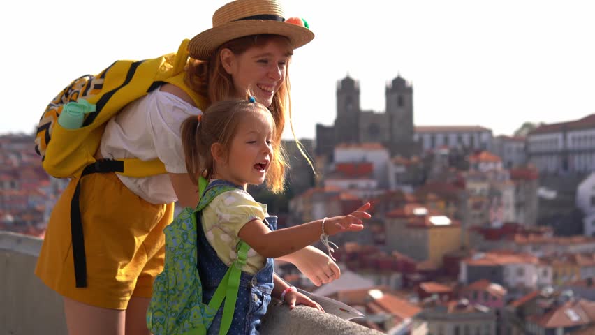 Happy family traveling. Young red-haired mother and little daughter looking on the Porto city, Portugal | Shutterstock HD Video #1099849629