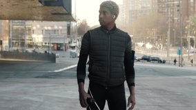 Cinematic video of a young African American exhausted runner athlete man drinking water and wiping his sweat in a city
