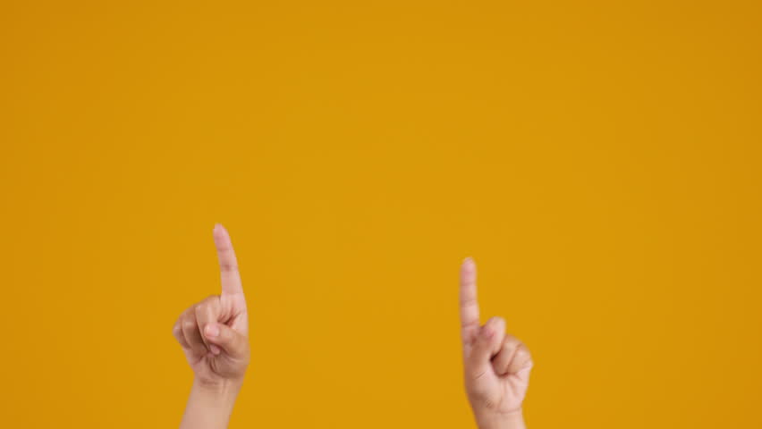 Two hands rising up and pointing up on yellow studio background with copy space