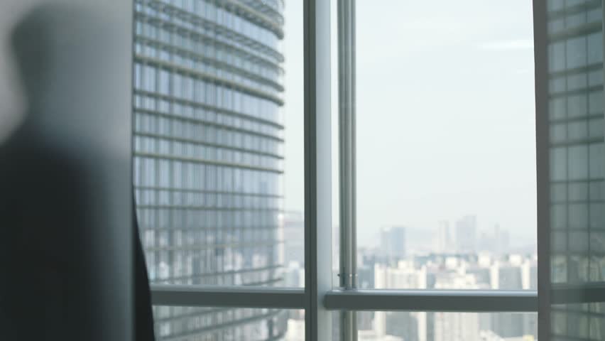 asian business man walking up to the window looking at the city in office Royalty-Free Stock Footage #1099854247