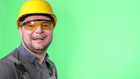 Happy smiling worker showing thumb up on green background in studio