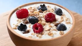 Yogurt with berries and muesli for breakfast in bowl on blue background