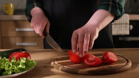 a man in the kitchen cuts a fresh tomato. salad preparation. raw vegetables on the table in sunny weather. High quality 4k footage
