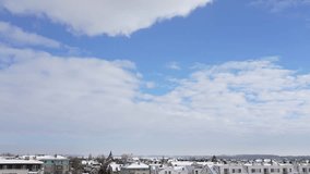 Beautiful winter sunny weather concept. 4k stock video time lapse of aerial view at small town in Europe in Poland. Roofs of many houses covered with fresh white snow and clouds running in blue sky