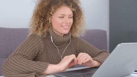 Cheerful curly woman speaking on web cam of a laptop. Portait of young female person talking on video call