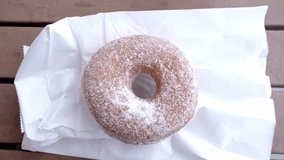 Zoom in of a sugar covered donut on top of a paper bag. Close up.