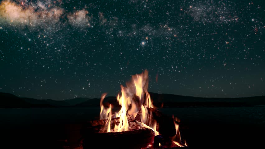 Bonfire burns at night against the background of mountains and sea with bright stars | Shutterstock HD Video #1099867265