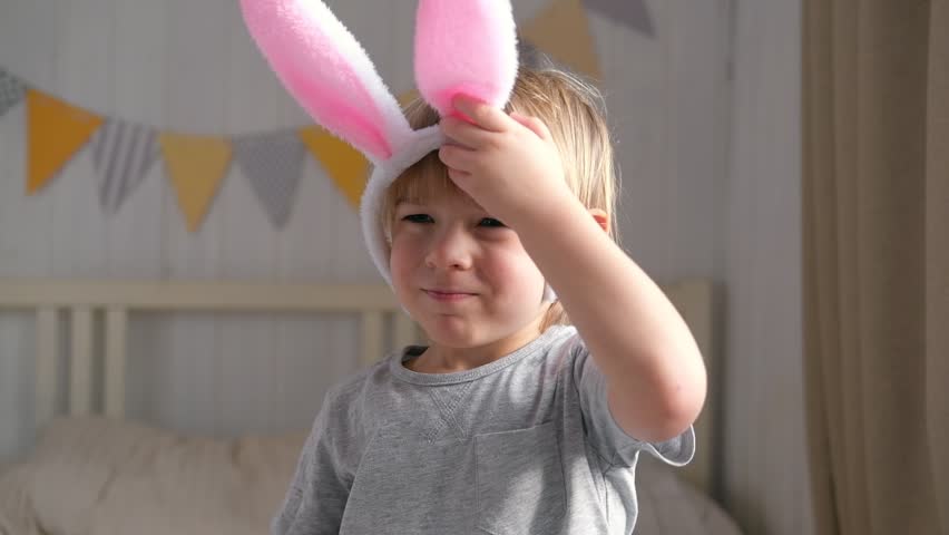 Portrait of adorable baby boy with bunny ears. Cute funny boy celebrating Easter at home. Surprised little kid. Spring. Traditional symbol of holiday and religion concept. Happy Easter. Easter child | Shutterstock HD Video #1099867735