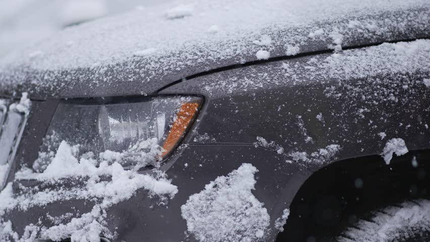 Unrecognizable man with brush clean white snow from car front headlight. Automobile cleaning in heavy snowfall. Snowstorm in winter season. Vehicle care in blizzard | Shutterstock HD Video #1099870693