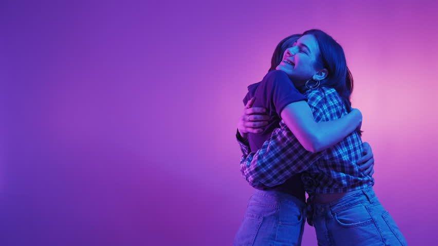 Best friends. Female relationship. Neon light people. Excited two women giving five together embracing and supporting each other on green violet background. | Shutterstock HD Video #1099871509