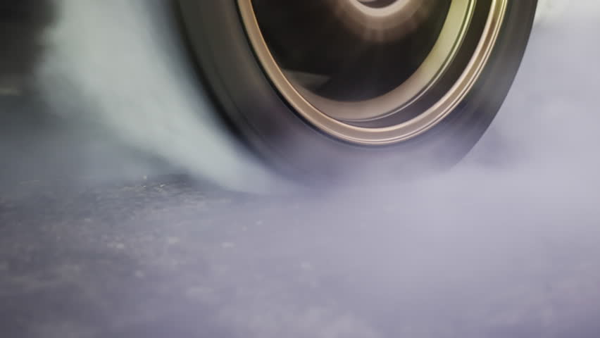 Drag racing car burning tire at starting line in race track.