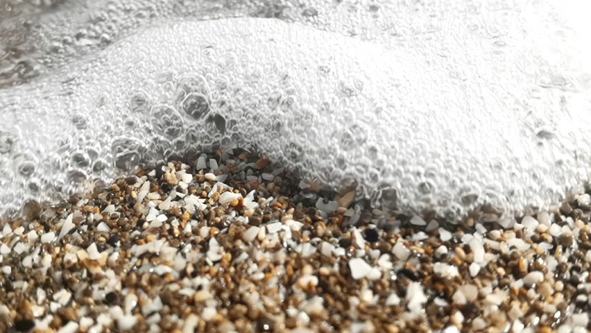 Slow motion of shells and pebbles on beach with sea as the tide comes in | Shutterstock HD Video #1099872811