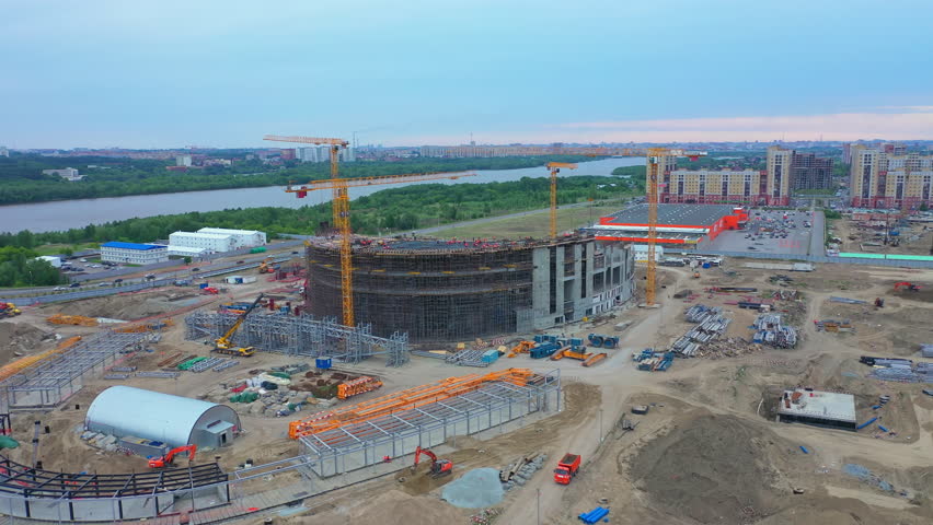 Sports center building and operating cranes at construction site in large city aerial view. Urban area development | Shutterstock HD Video #1099873641
