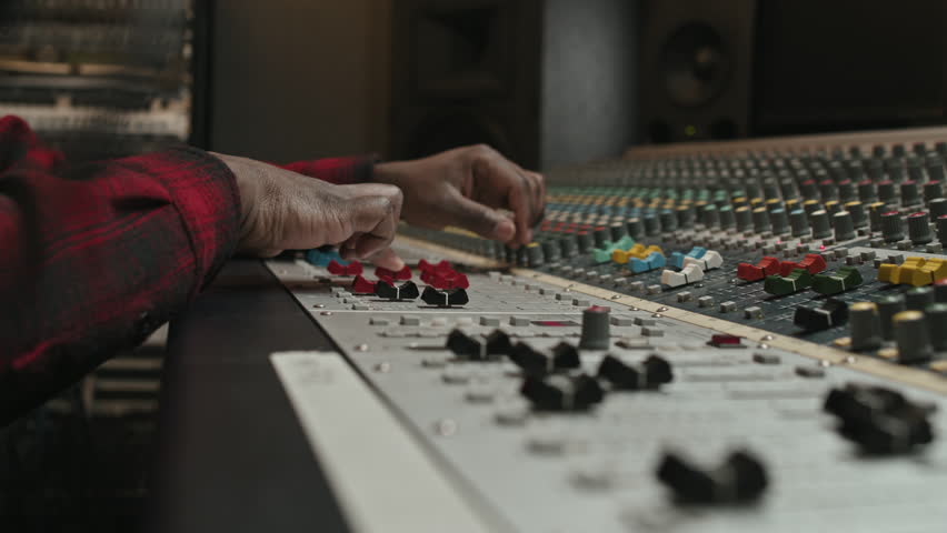 Close-up of young black man adjusting consoles on sound mixer while creating new music and recording it in modern studio | Shutterstock HD Video #1099874967