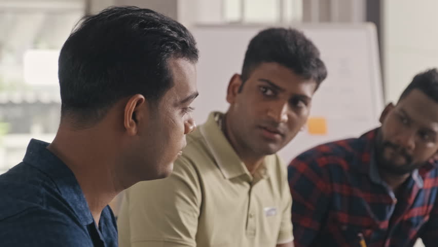 Group of Indian software developers discussing IT project and writing down notes during team meeting in office | Shutterstock HD Video #1099876517