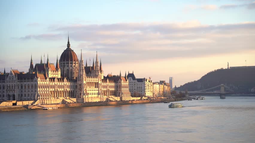 Hungarian parliament building at sunset, Budapest, Hungary. Danube River Cruise boat. | Shutterstock HD Video #1099878345