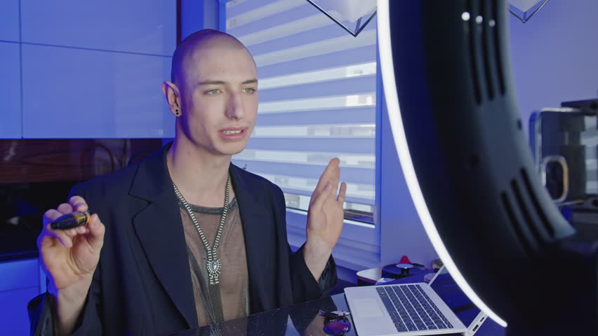 handsome gay man talking in a live video and recording makeup tutorial, medium shot. High quality 4k footage