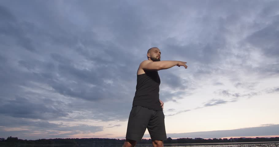 A young man is doing sports in nature near the river