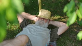 High angle view of carefree relaxed senior man in straw hat with closed eyes sleeping in summer spring garden. Happy Caucasian old gardener taking a nap outdoors on sunny day. Slow motion - Powered by Shutterstock - Get 15% off with code: PIKWIZARD15