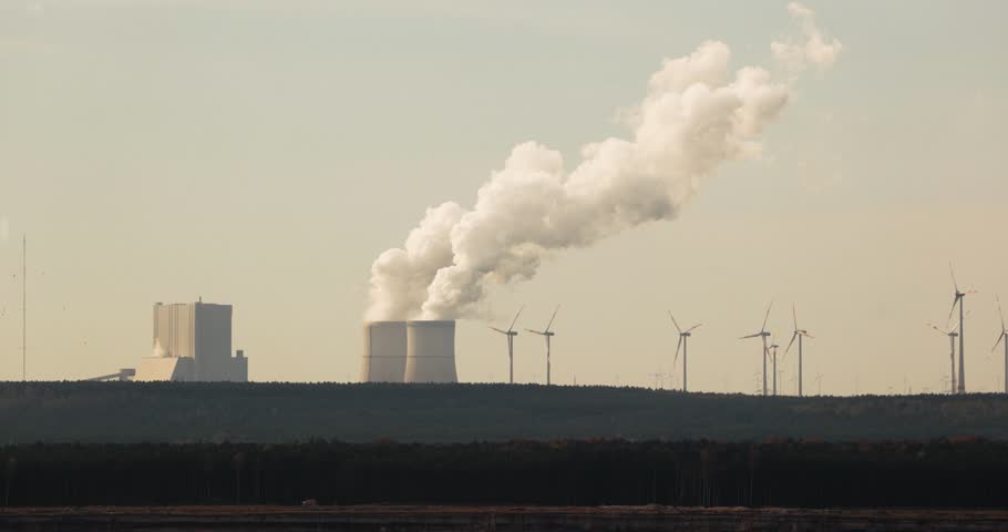 Power plant cooling towers emiting steam. Coal power station Schwartze Pumpe, Germany, wind turbanies nearby