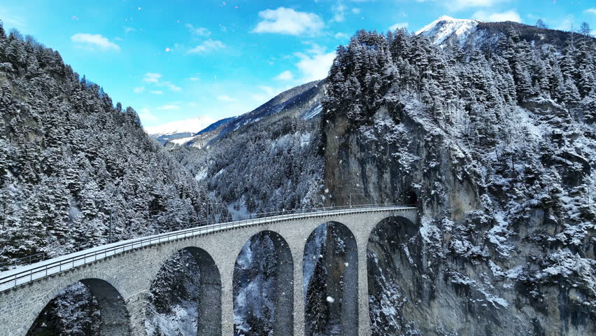 Aerial view of Train passing through famous mountain in Filisur, Switzerland. Landwasser Viaduct world heritage with train express in Swiss Alps snow winter scenery.