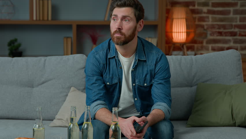 Caucasian adult single man sit at home party alone no guests lonely birthday. Sad unhappy bearded male in despair middle-aged crisis look at table with pizza and beer loneliness isolation quarantine