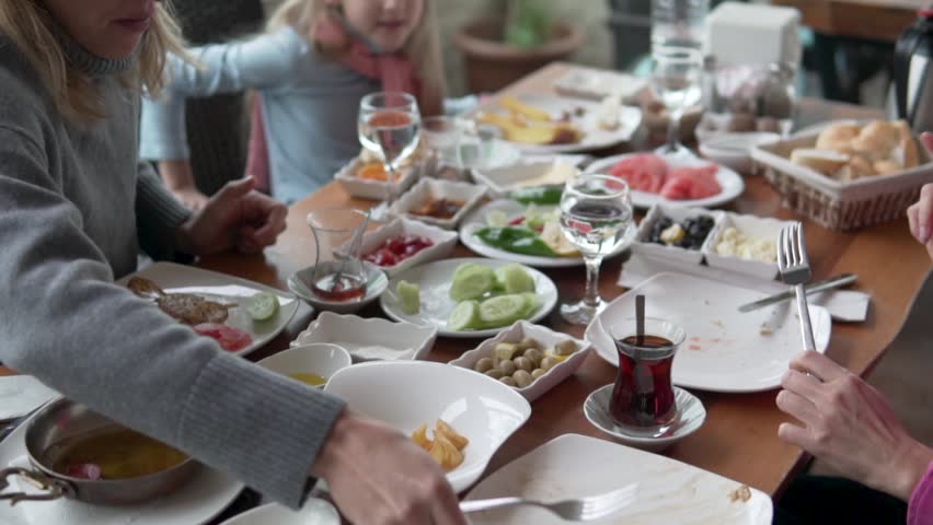People eat at the table with lots of plates of food.
