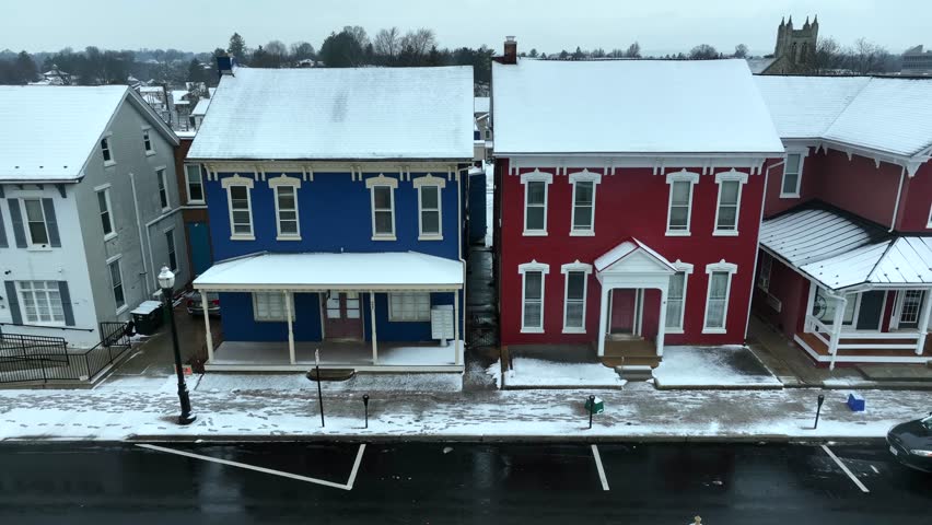 Blue and red houses in small town America. Aerial rising shot of snow covered homes. Quaint housing in small city.
