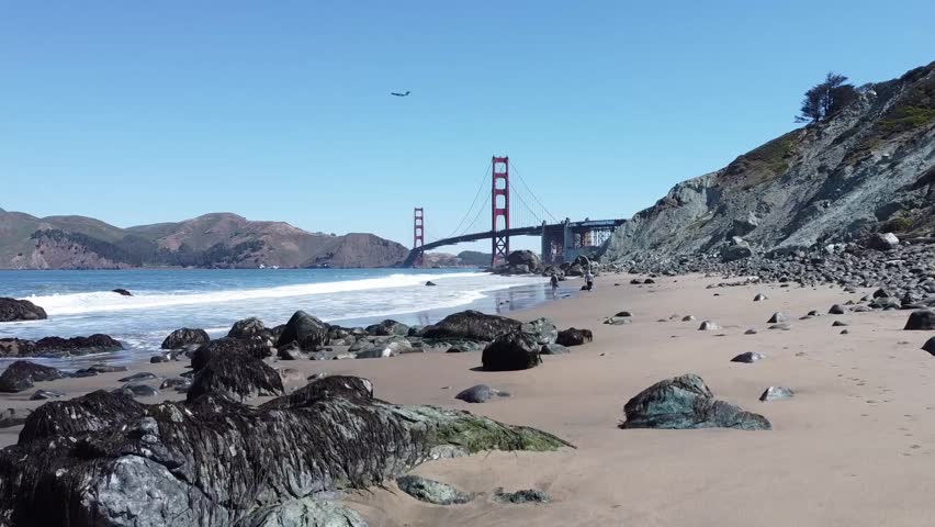 Rising shot of Golden Gate Bridge at Baker Beach with waves crashing