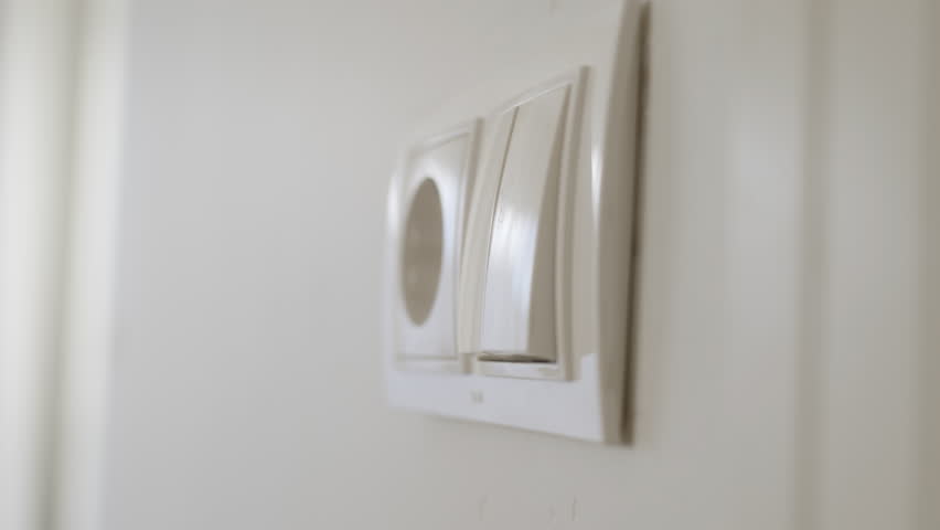 Man hand turn off light in room. button of inclusion and switching off of light combined with 220 volt socket in living room.