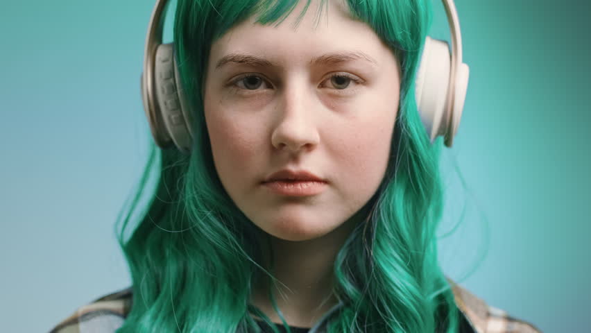 Generation Z concept. Video portrait of beautiful young woman with green coloured hair wearing headphones. Royalty-Free Stock Footage #1099896871