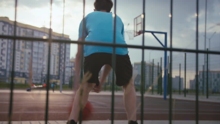 Young man training with a basketball at sunset on the court, back view, cinematic, basketball games in the residential area | Shutterstock HD Video #1099901487