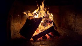 Slow motion 4K video of burning dry woods in the brick outdoor country house mantel at the cold autumn late evening. Home coziness and energy saving concept footage.