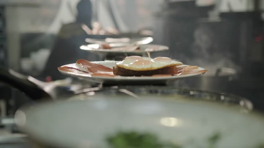 Chef in a restaurant kitchen serve fried eggs | Shutterstock HD Video #1099905029