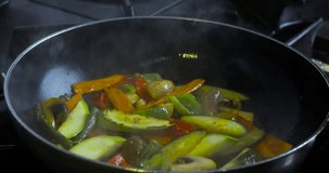 Vegetables in a frying pan are cooked on fire

