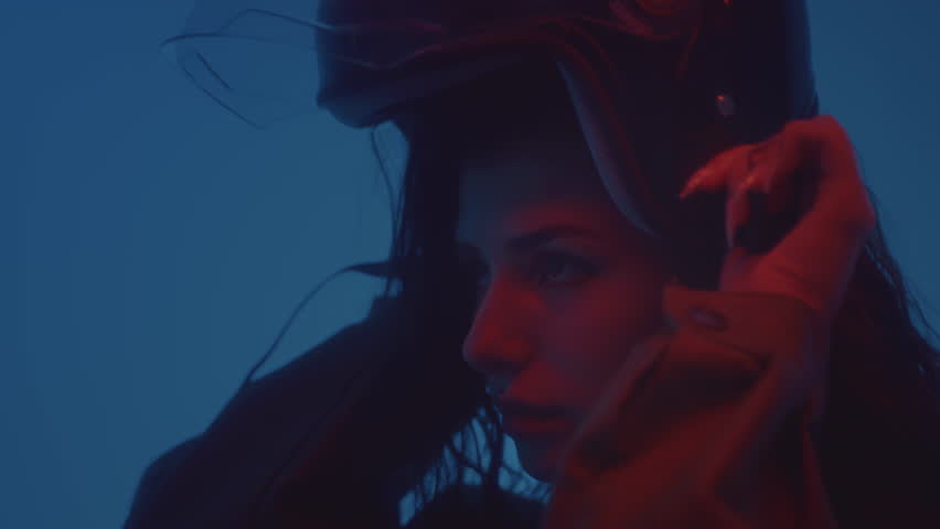 A young attractive girl puts on a helmet. A beautiful woman in a leather jacket puts on a plastic protective helmet for a motorcycle or scooter. Urban lifestyle. Independent and strong girl, feminism