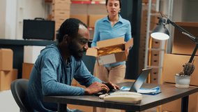 Small business owners doing distribution quality control for startup development, working on stock shipment with laptop at warehouse. Young people doing teamork to ship merchandise. Handheld shot. - Powered by Shutterstock - Get 15% off with code: PIKWIZARD15